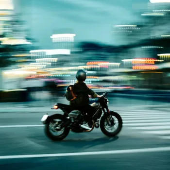 Motard roulant rapidement en ville avec des lumières floues en arrière-plan