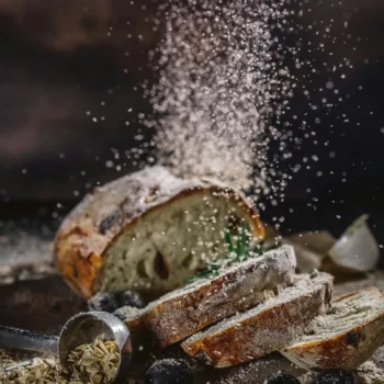 Pain artisanal saupoudré de farine avec olives et herbes sur une table rustique