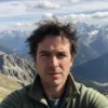 Homme en plein air devant un paysage de montagne.