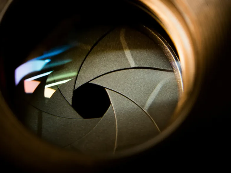 Vue rapprochée d'un diaphragme d'objectif d'appareil photo ouvert avec des reflets colorés
